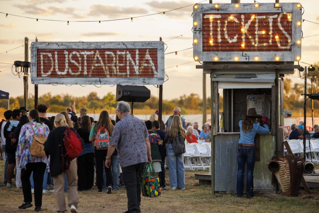 People gather near a ticket booth and a sign reading 