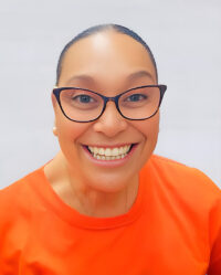 A person with glasses, a wide smile, and wearing an orange shirt, pictured against a light background.