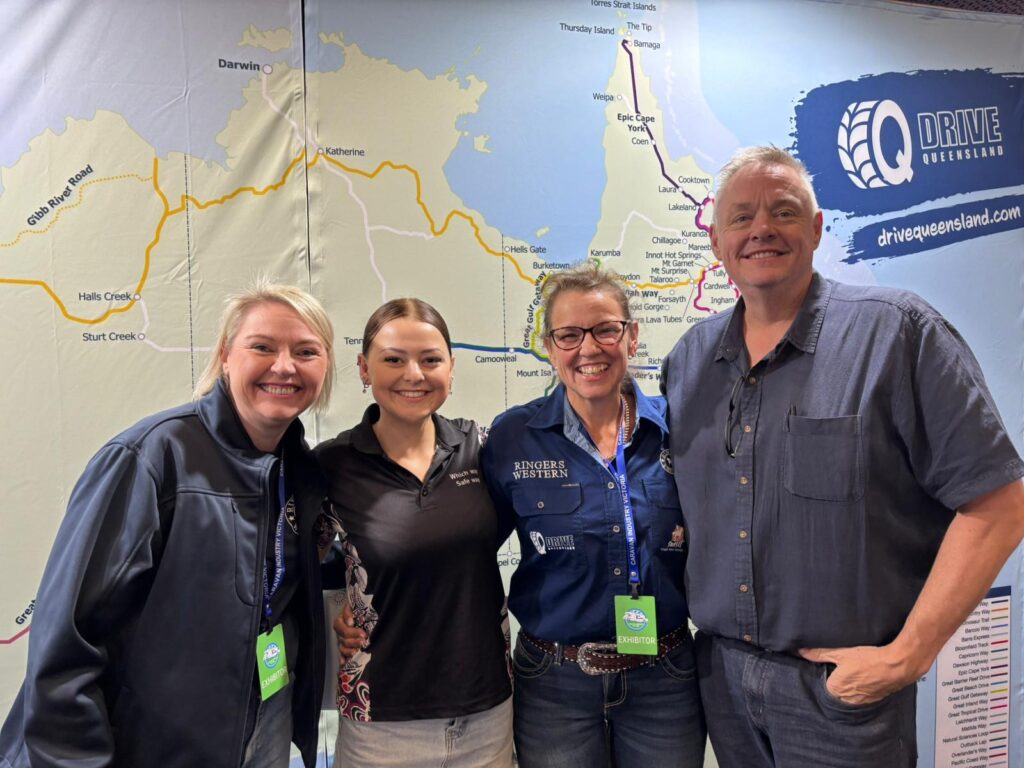 Four people stand smiling in front of a large map and a 