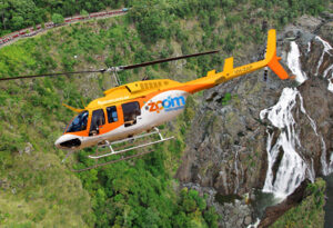 A yellow and white Zoom Helicopter flies over a green landscape with a waterfall and a train visible in the background.