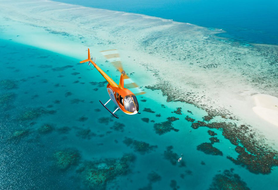 An orange helicopter flies over a coral reef and clear turquoise water near a sandy shoreline.